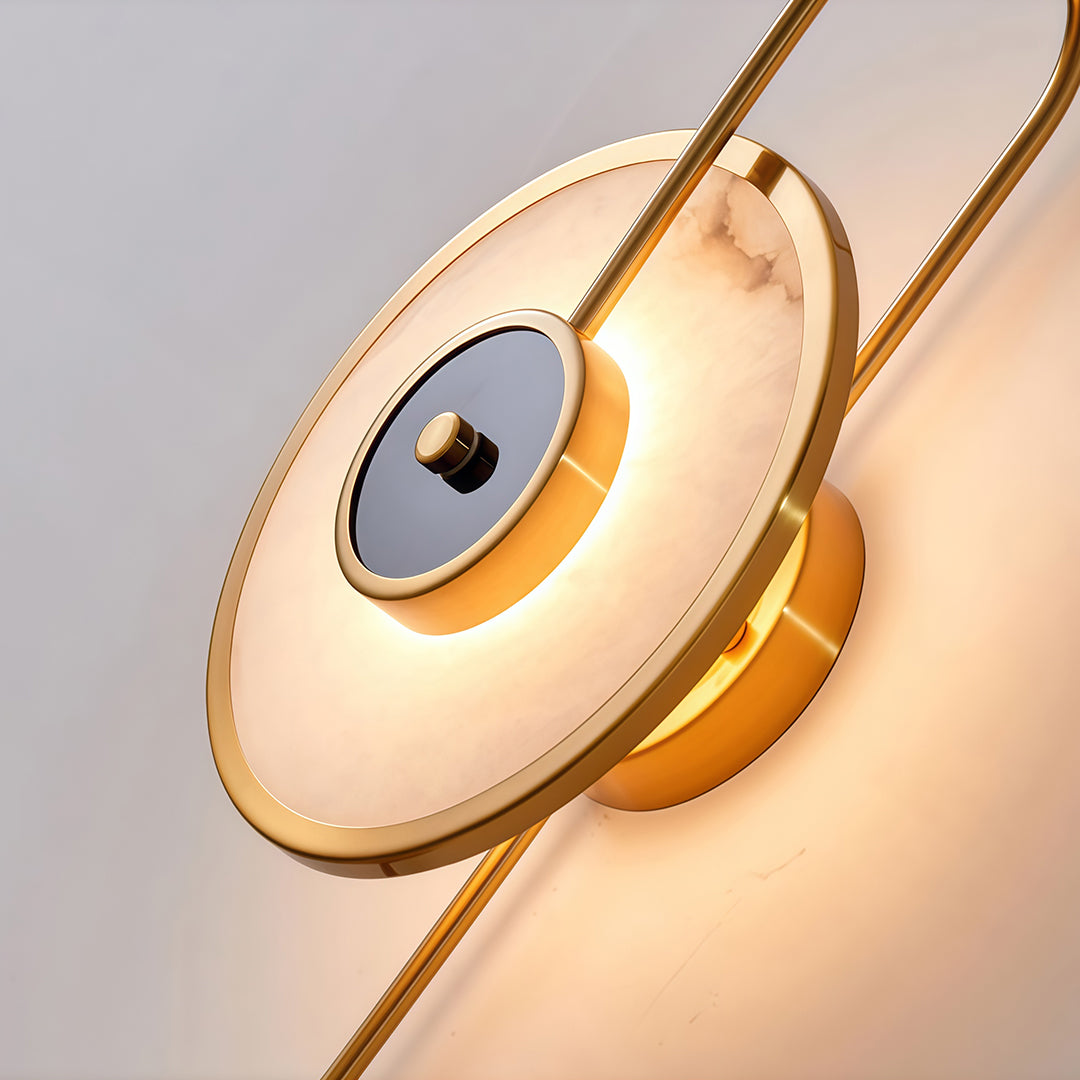 Close-up detail of marble wall light showing brass construction and illuminated circular halo design
