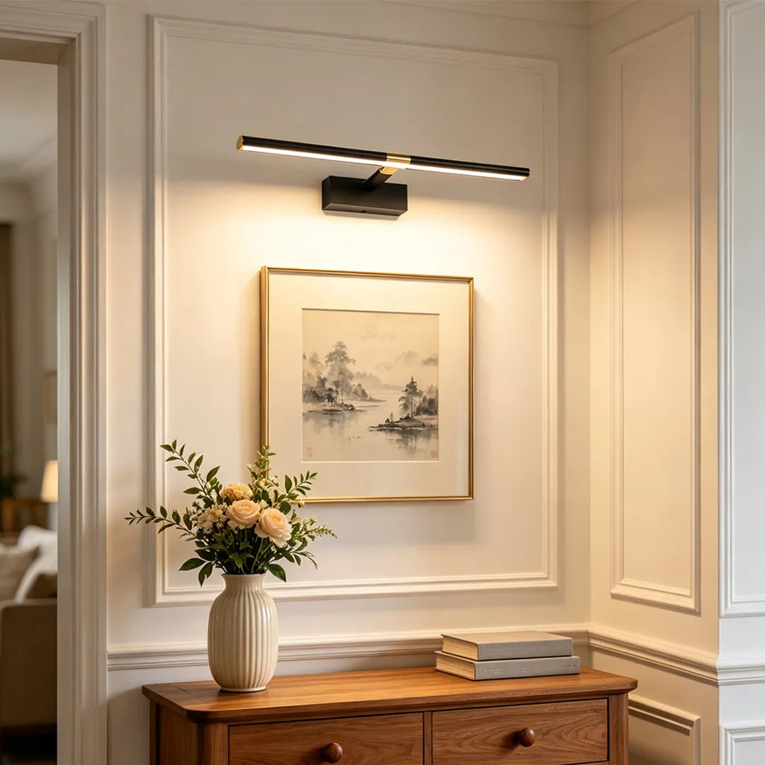 Master bathroom vanity lights with a slim black and gold bar design mounted above framed wall art.