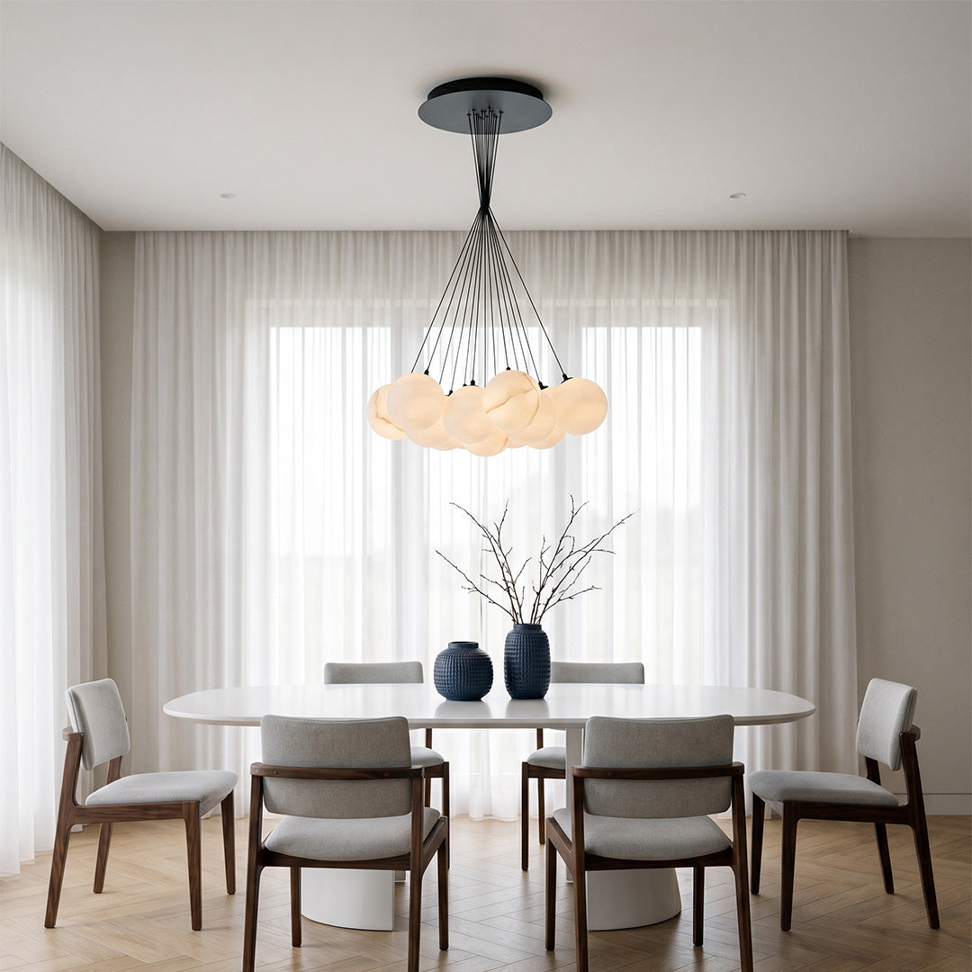 Matte black chandelier with multiple hanging globes illuminating a minimalist dining space with neutral tones.
