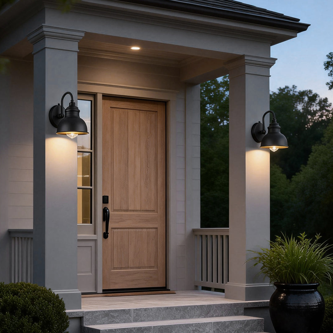 Matte black gooseneck light mounted beside a front porch door, providing warm downward illumination for a classic outdoor entryway.