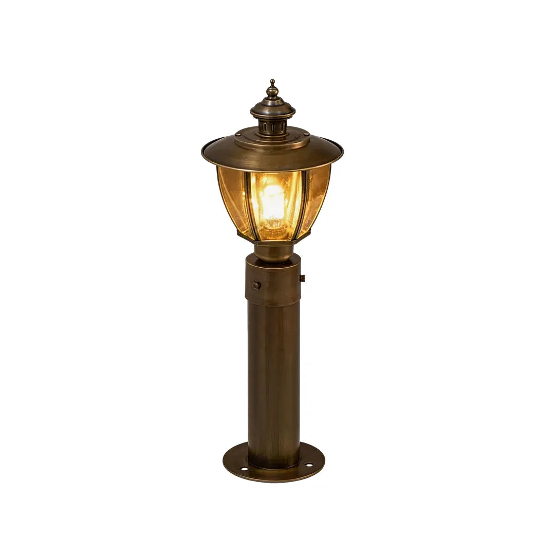 Medium vintage brass bollard light with clear glass lantern and warm glow