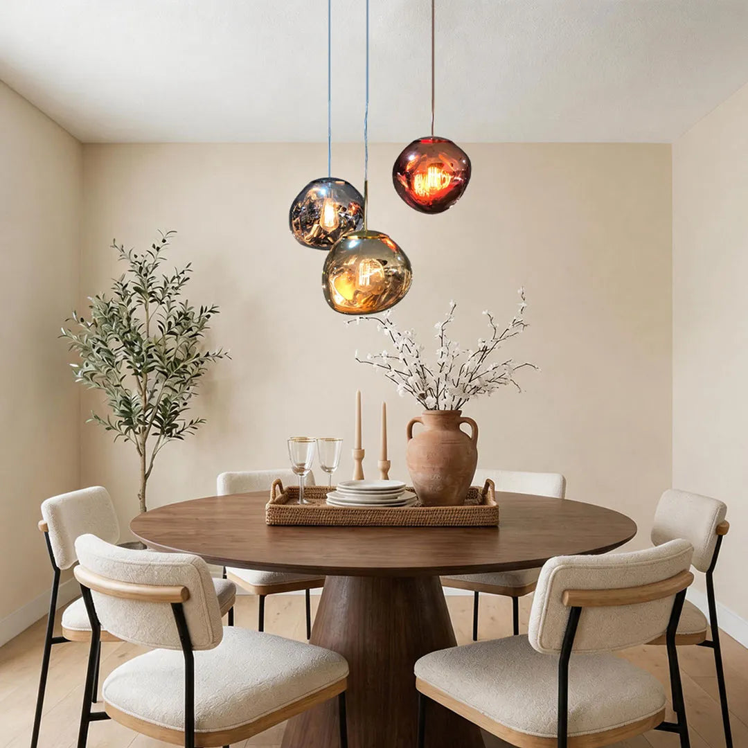 Melt pendant light trio hanging above a round dining table in a warm modern dining room.
