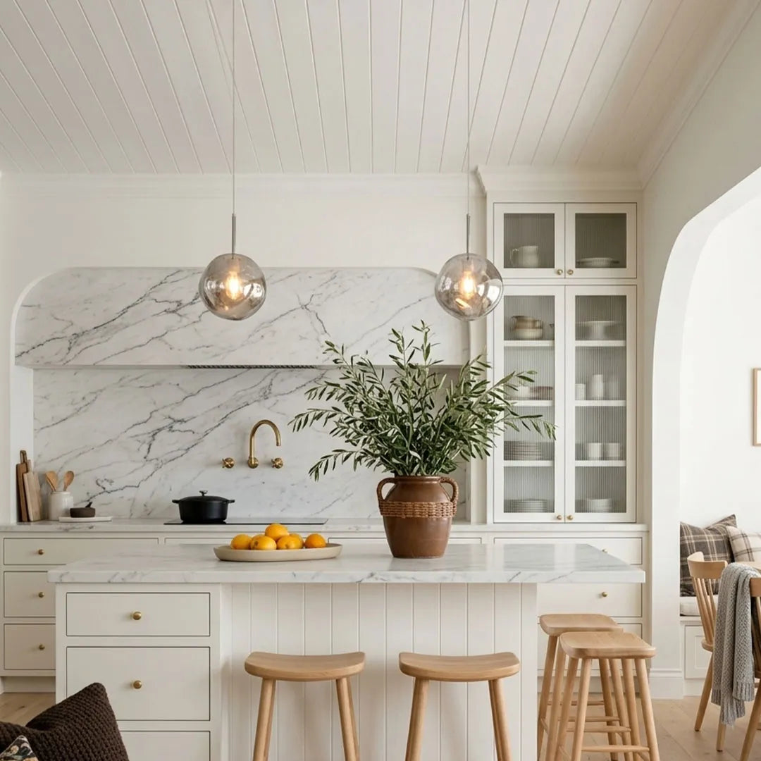 Melt pendant lights suspended above a white kitchen island with a marble backsplash and light cabinetry.