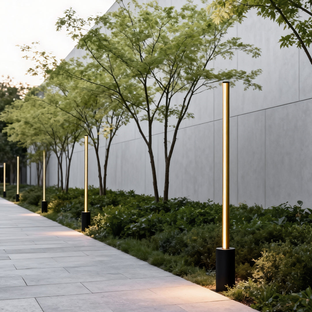 Weather resistant metal contemporary outdoor floor lamps lining a landscaped garden pathway with trees.