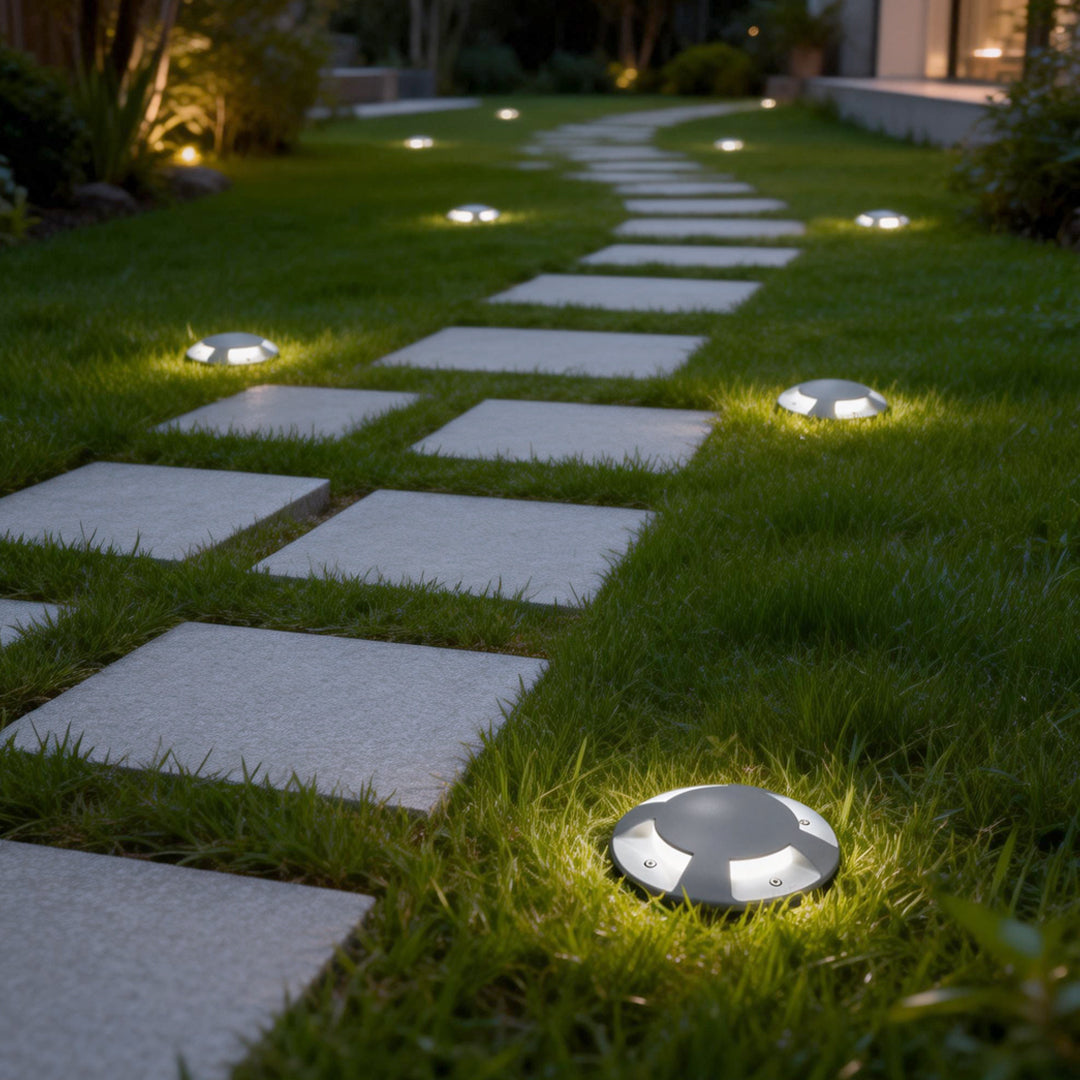 Metal deck lights illuminating a modern garden pathway with warm ambient glow.