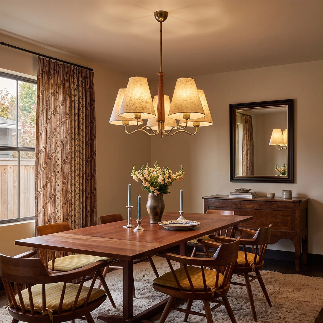 Metal dining room chandelier suspended above a wooden dining table in a cozy dining room with woven chairs and floral curtains.