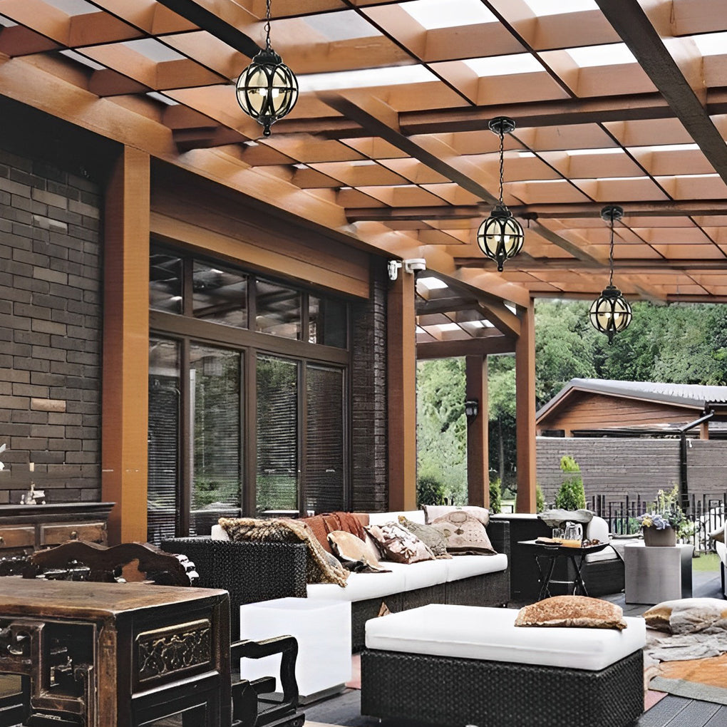 Metal orb pendant light used in a modern outdoor living space with wood ceiling and comfortable seating.