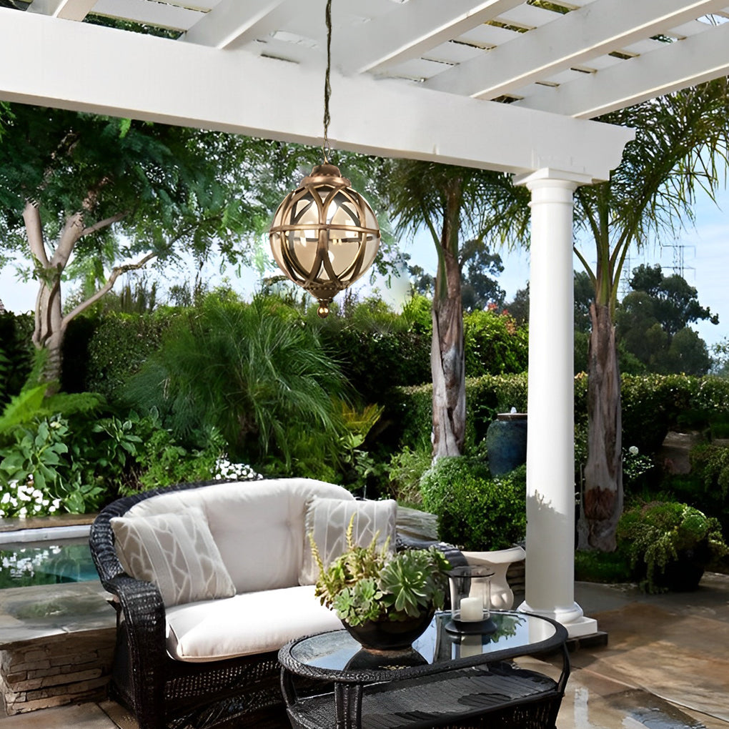 Metal orb pendant light hanging from a pergola over an outdoor lounge, adding decorative and functional lighting.
