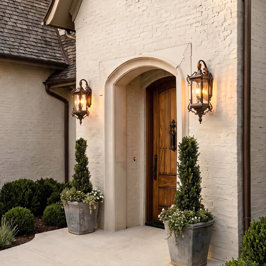 Metal outdoor wall sconces on a white stucco entryway, highlighting an arched doorway with elegant traditional lantern lighting.