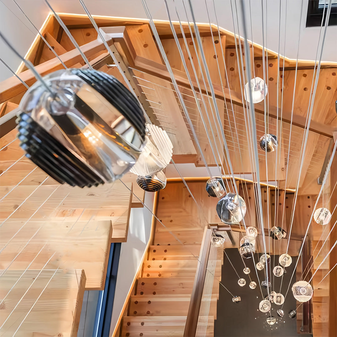 Metal pendant lights with smoked glass shades, hanging in a multi-level arrangement along a staircase.
