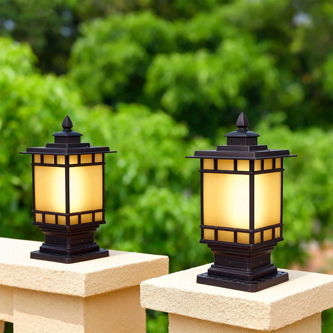 Pair of matching metal pillar lights mounted on white pedestals creating symmetrical entrance lighting