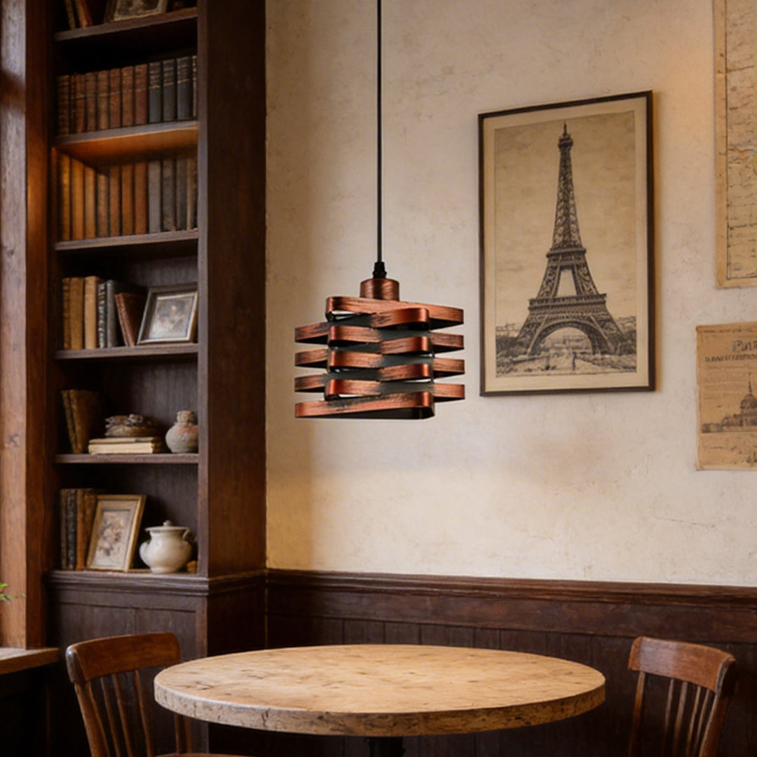 Metal ribbon pendant light installed above round table in vintage cafe setting.