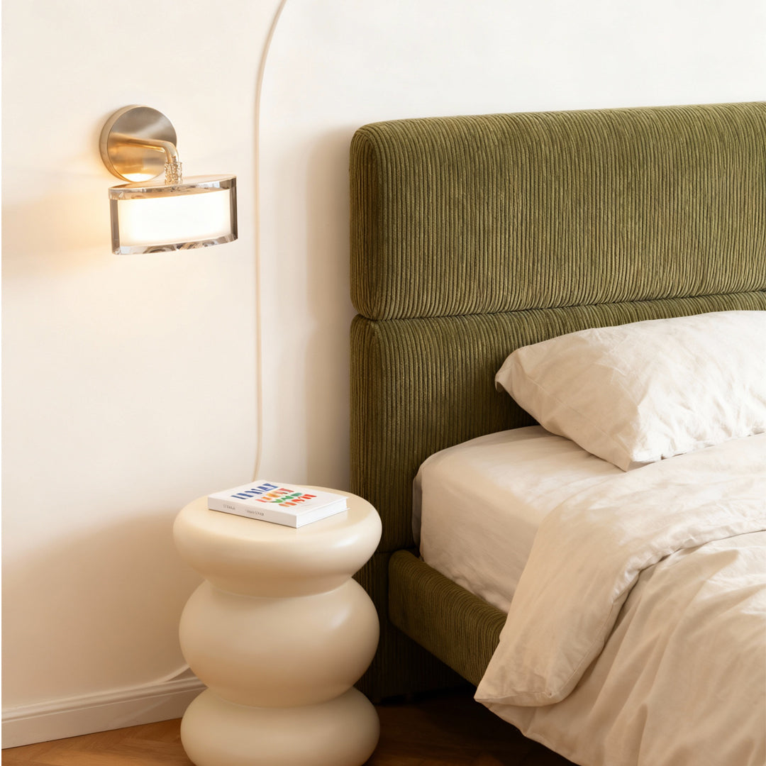 Metal wall art with led lights mounted beside bed with tufted green velvet headboard creating warm ambient glow