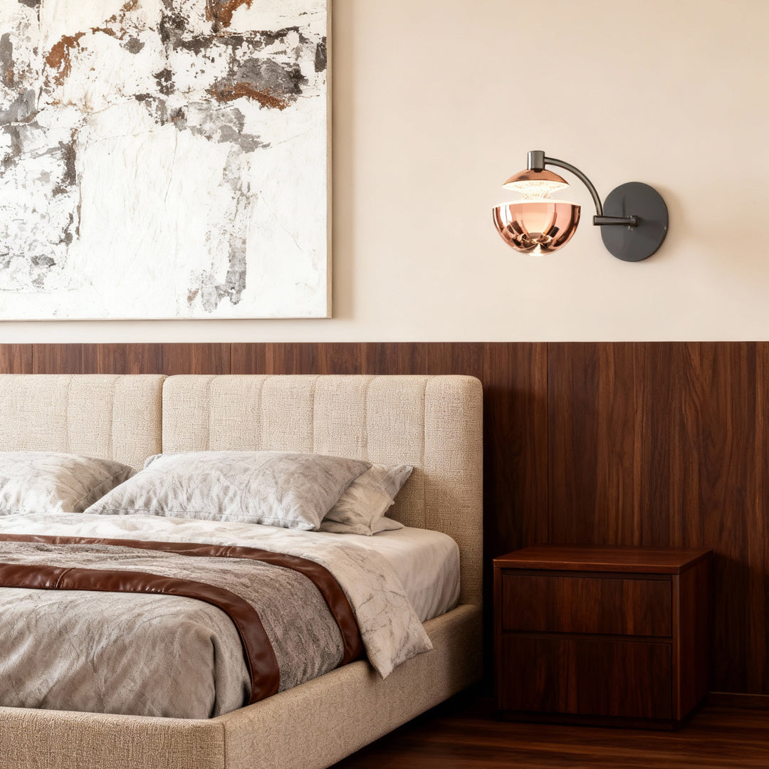 Metal wall sconce illuminating bedroom corner with dark wood furniture and tufted upholstered headboard in contemporary setting