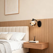 Metal wall sconce mounted beside floating nightstand in minimalist bedroom with natural wood paneling and neutral palette