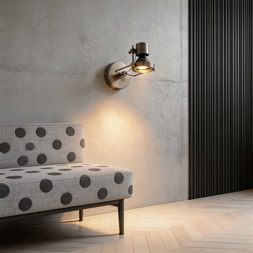 Metallic industrial wall lights above a polka dot chair in a minimalist living room interior.