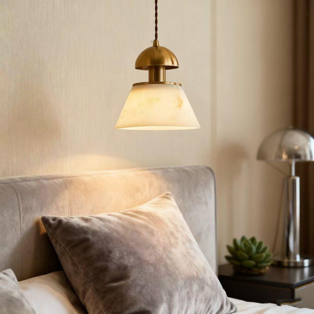 Metallic pendant lights suspended beside bed in contemporary bedroom with neutral palette and soft textile accents