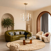 Mid-century retro chandeliers with chrome accents and curving arms, lighting a chic living room with a green leather sofa.