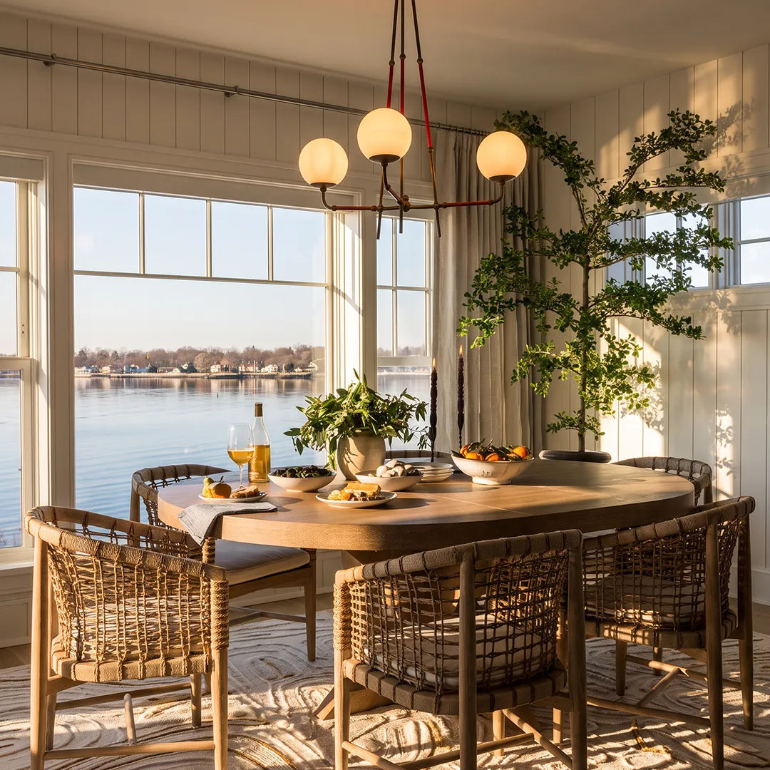 Mid century modern chandelier displayed above a dining table in a bright breakfast room with water views.