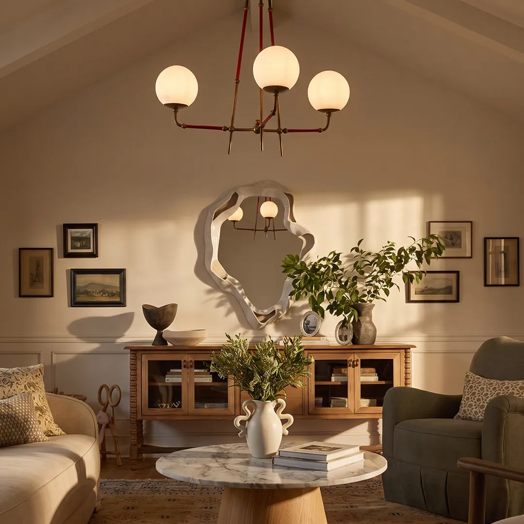 Mid century modern chandelier lighting a cozy living room with a sculptural mirror and wood console.
