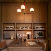 Mid century modern chandelier hanging above a built-in desk in a warm wood home office.