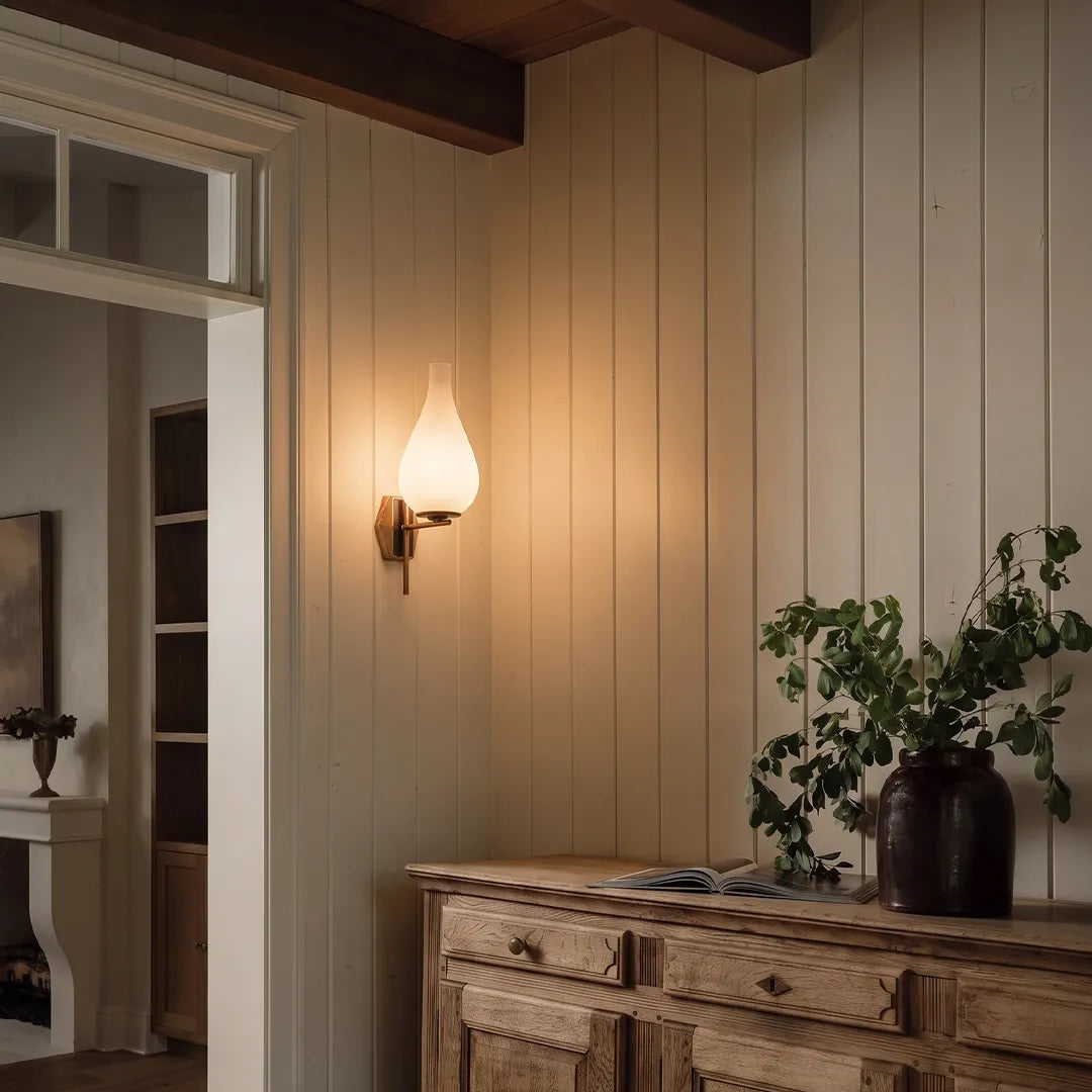 Mid century modern wall light mounted on a paneled bedroom wall with a soft warm glow.