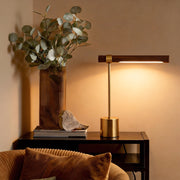 Mid century modern wood and brass lamp illuminating a cozy reading nook with warm, ambient glow.
