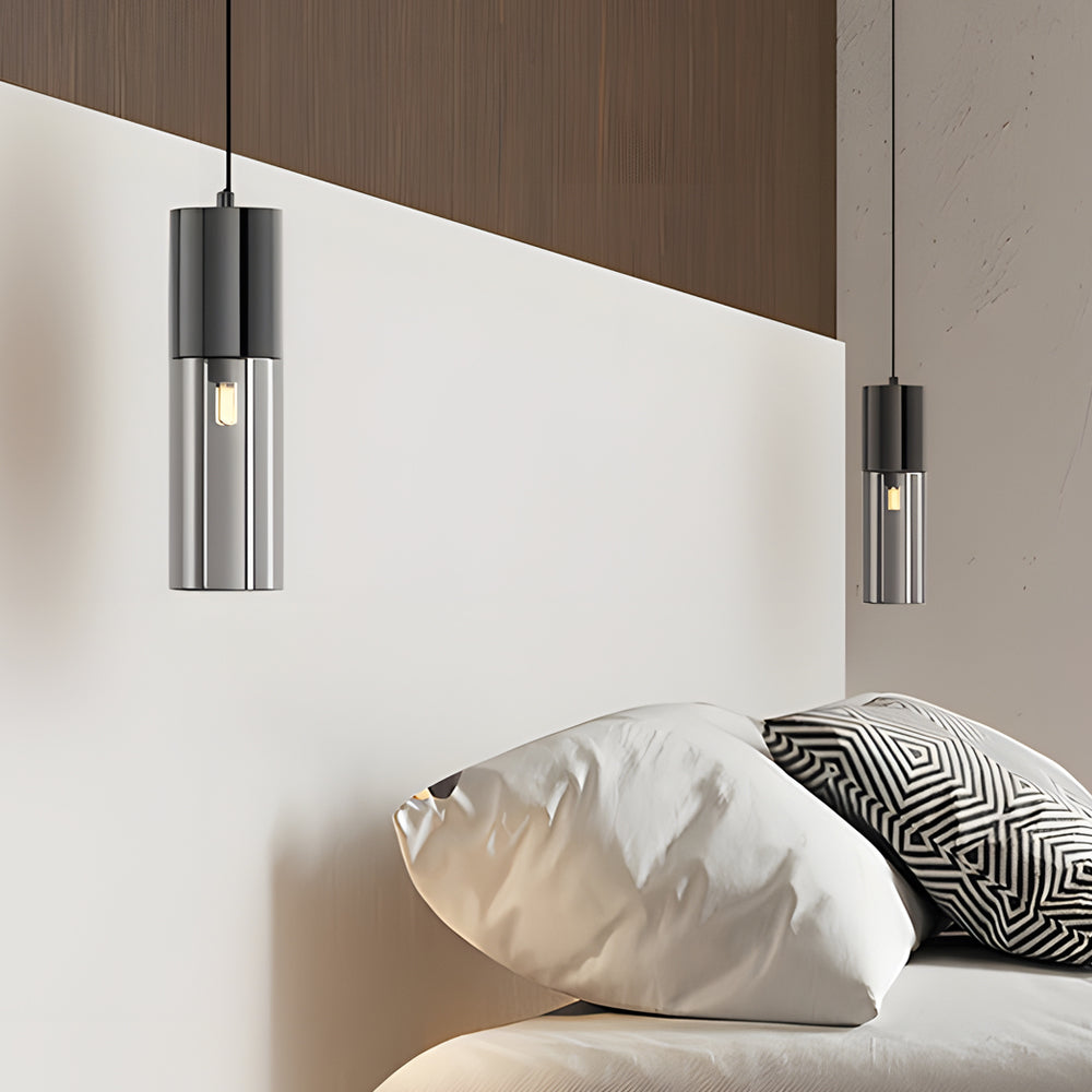 Mini black pendant light hanging next to a bed against a wall