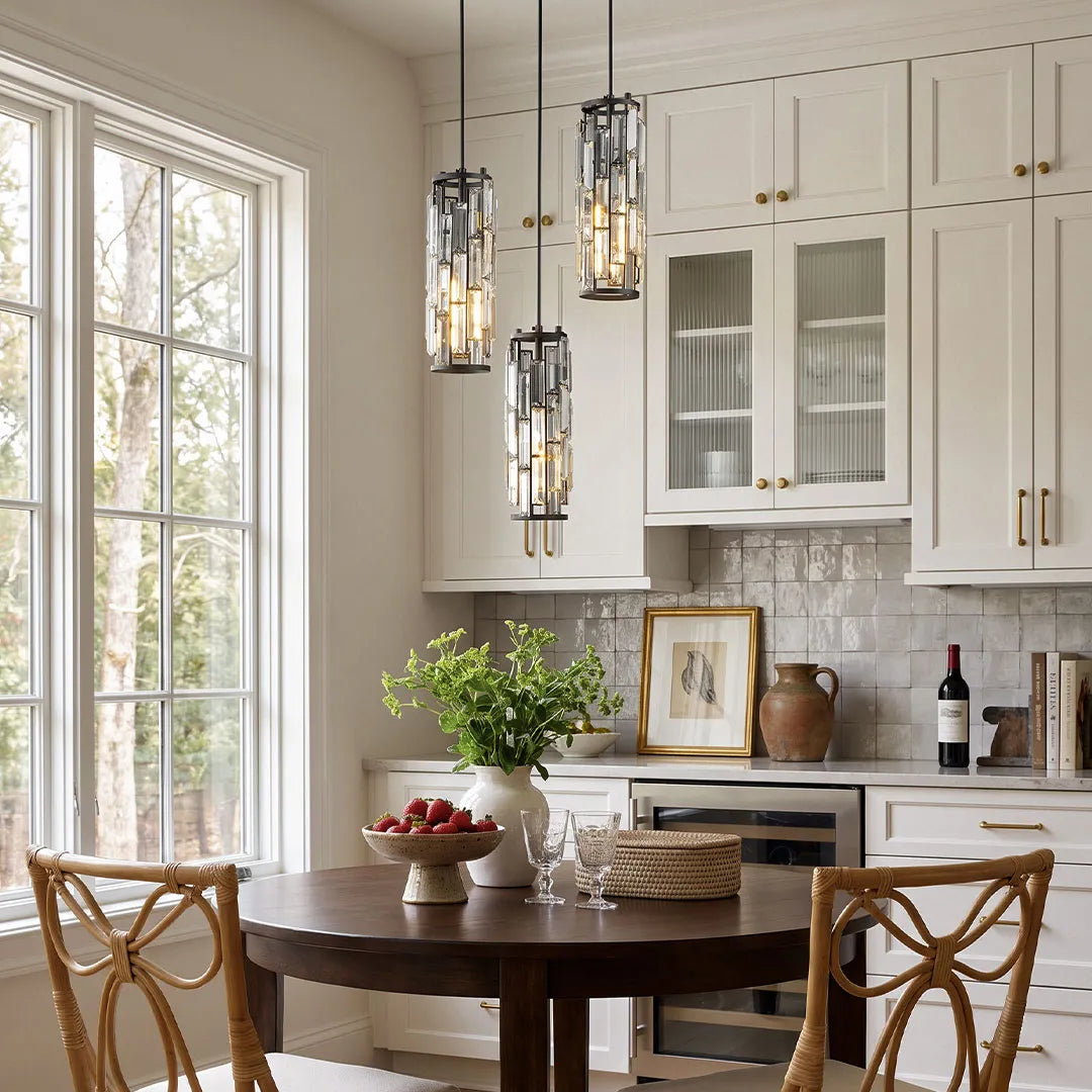 Mini crystal pendant light set in a dark finish displayed above a dining table beside tall kitchen windows.