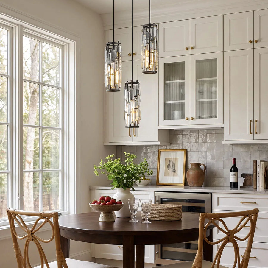 Mini crystal pendant light set in a dark finish displayed above a dining table beside tall kitchen windows.