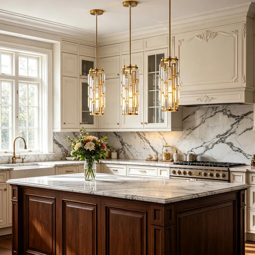 Mini crystal pendant light in a gold finish suspended over a marble kitchen island in a classic white kitchen.