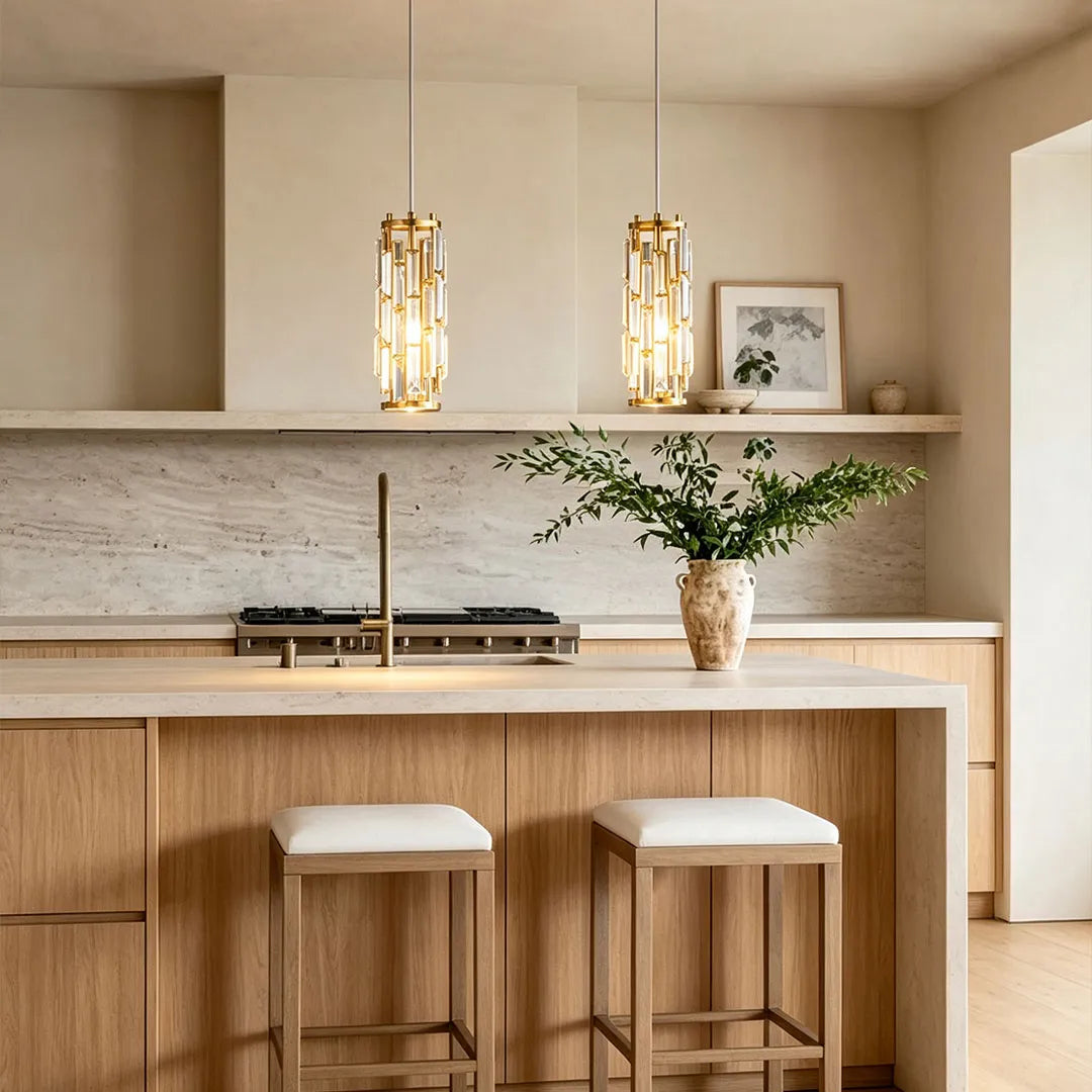 Mini crystal pendant light pair in a gold finish illuminating a warm minimalist kitchen counter.