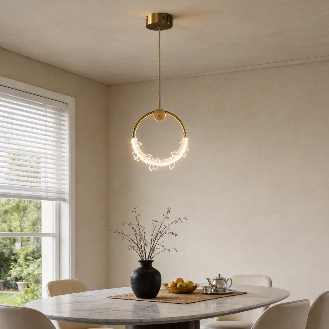 Mini crystal ring pendant light with a golden frame, hanging above a modern dining table.
