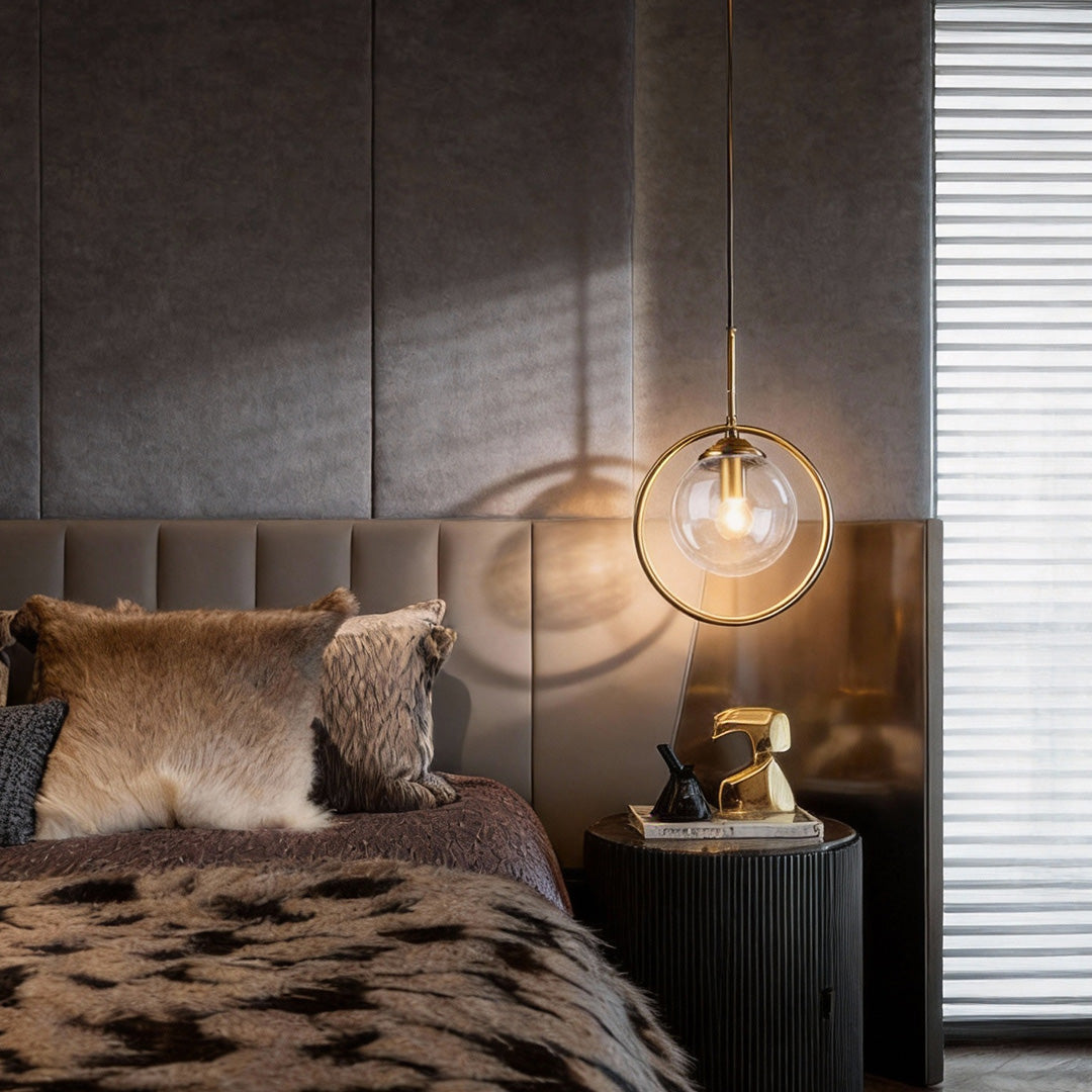 Mini gold pendant light providing soft light beside a contemporary bed.