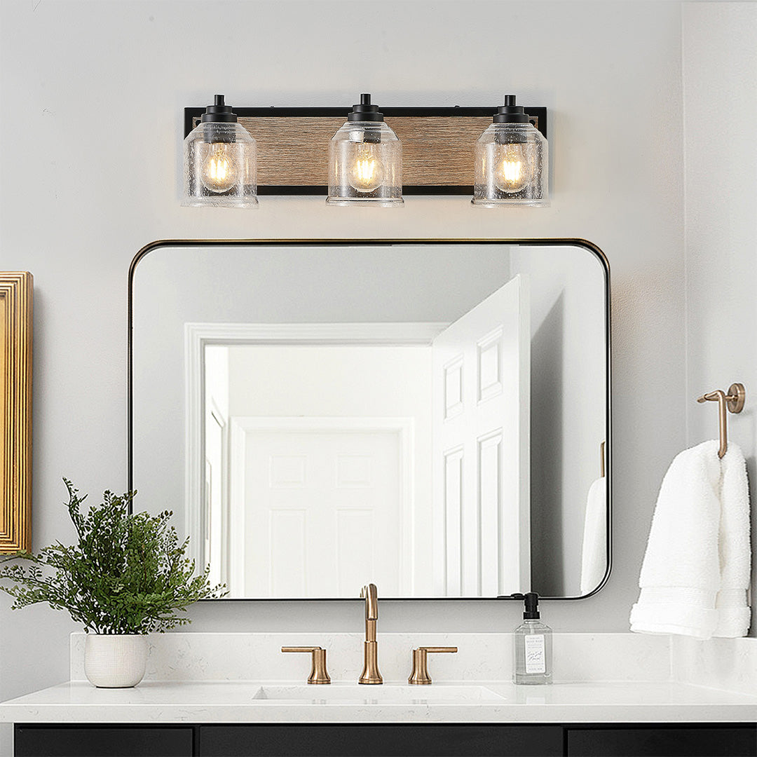 Multi-light wall sconce with clear glass shades, installed in a minimalist bathroom for a clean and bright look.