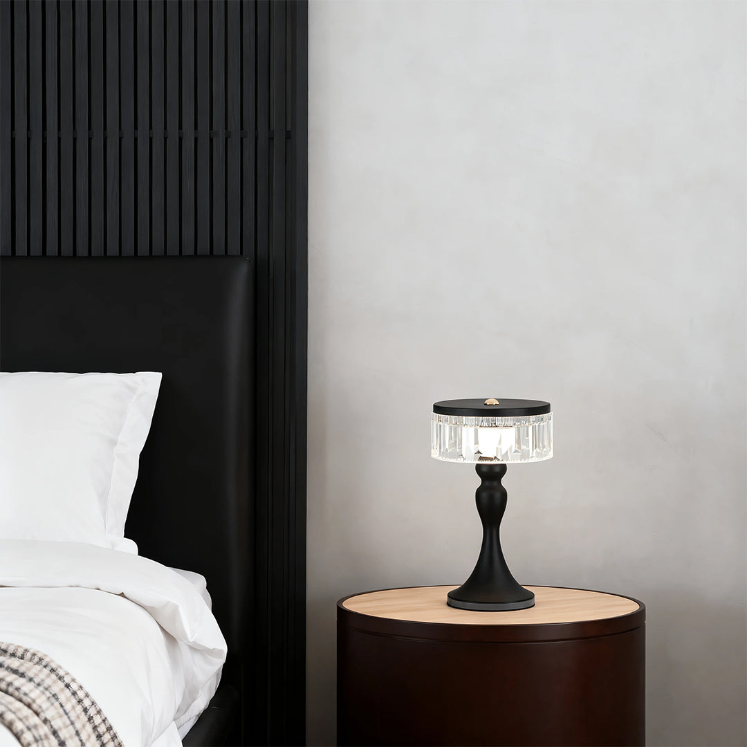 Minimalist black forged iron table lamps style providing soft ambient light on a dark round side table in a bedroom.