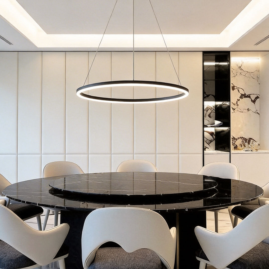 Minimalist black LED ring chandelier over a luxury black marble dining table with white chairs.