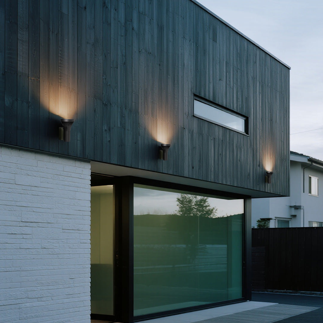 Architectural design highlighted by three minimalist black Outdoor Wall Lighting Fixtures on a dark wood and white brick facade.
