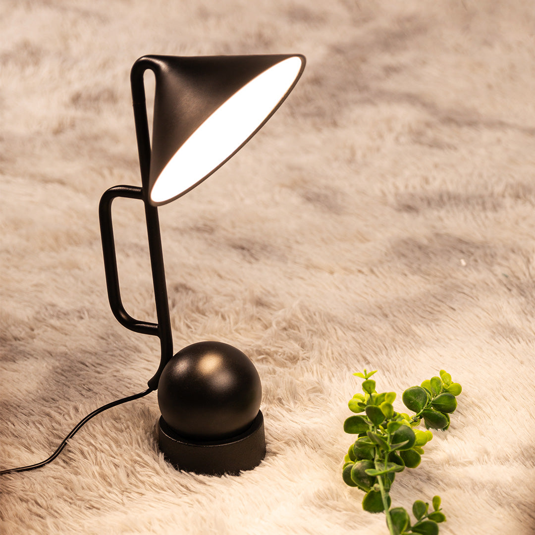 Minimalist black metal USB rechargeable table lamp with plant accent on textured surface