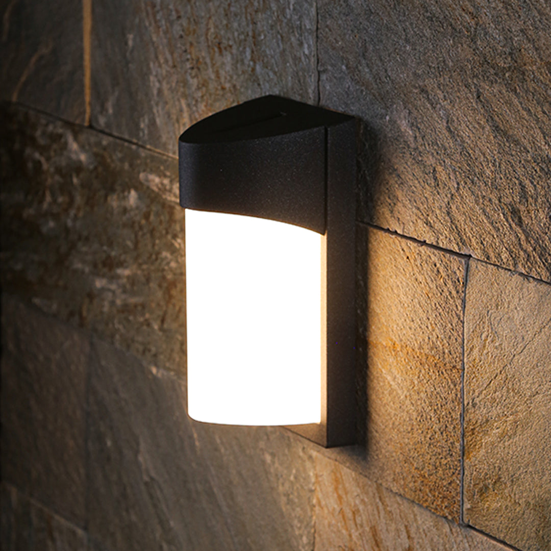 Minimalist black wall lights installed on textured stone exterior creating warm ambient illumination