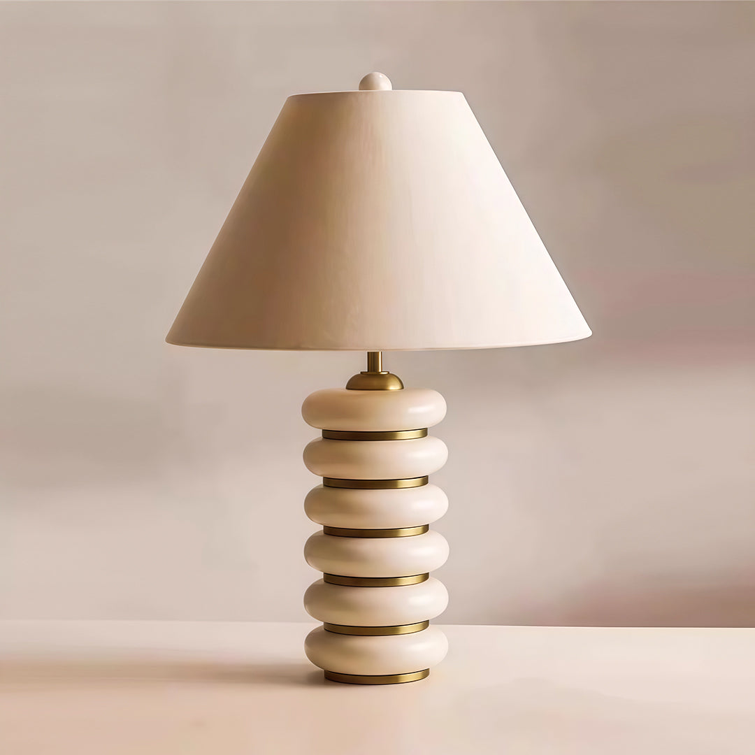 Minimalist cloth table lamp with glass shade chandelier design in light wood finish with stacked disc silhouette on neutral background.