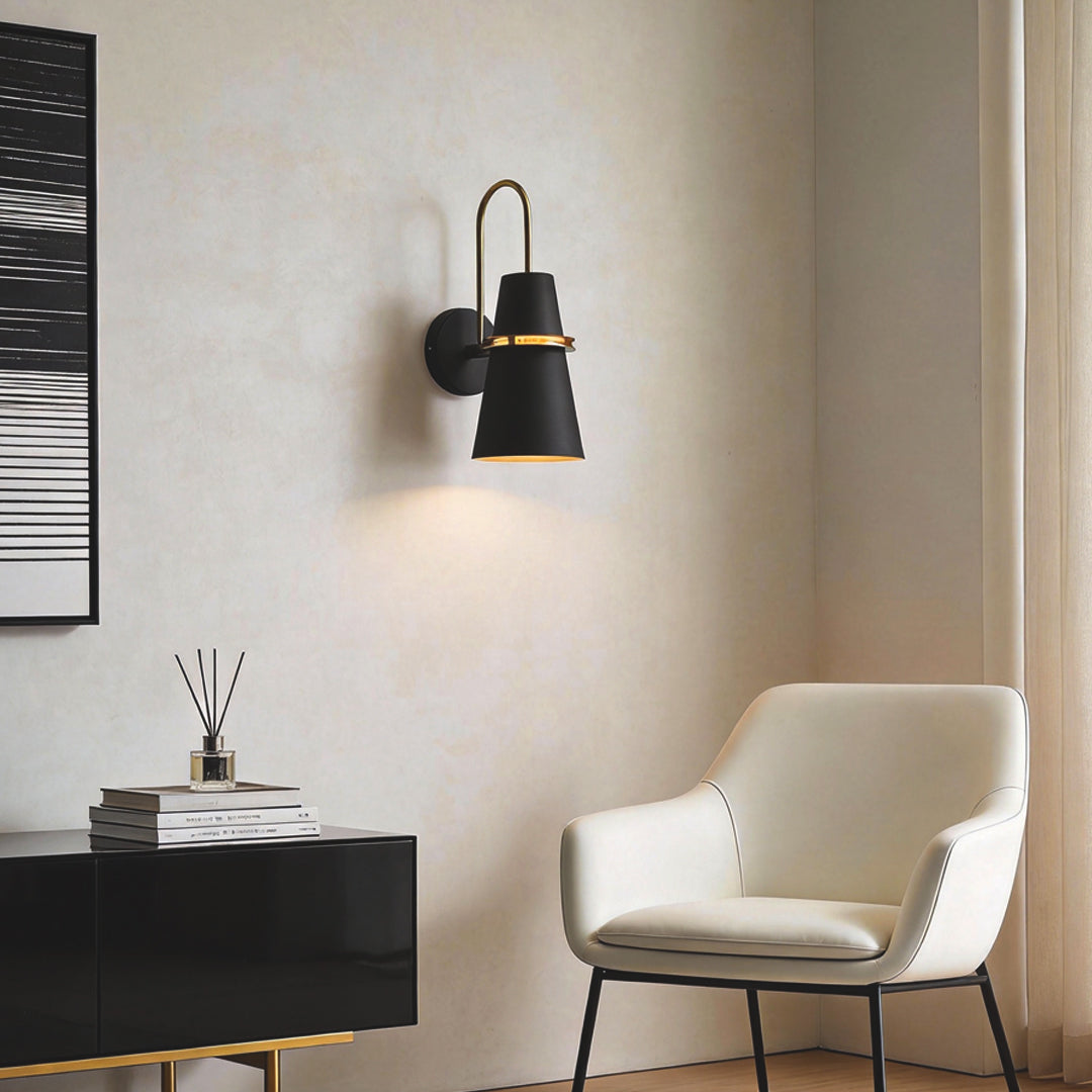 Minimalist black cone wall lamp installed beside armchair in a contemporary reading corner.