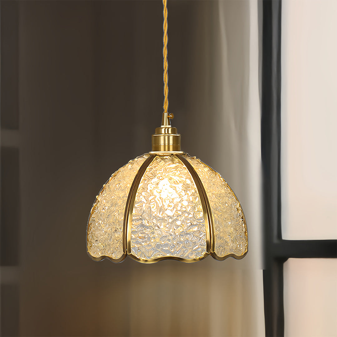 Small crystal pendant light with warm glow suspended in minimalist interior space