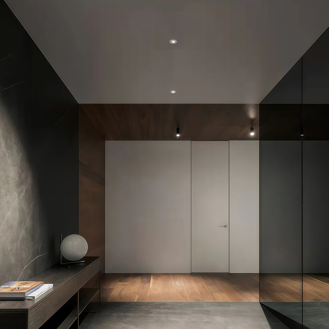 Minimalist dark interior with discreet ceiling-mounted modern spotlights providing focused illumination.