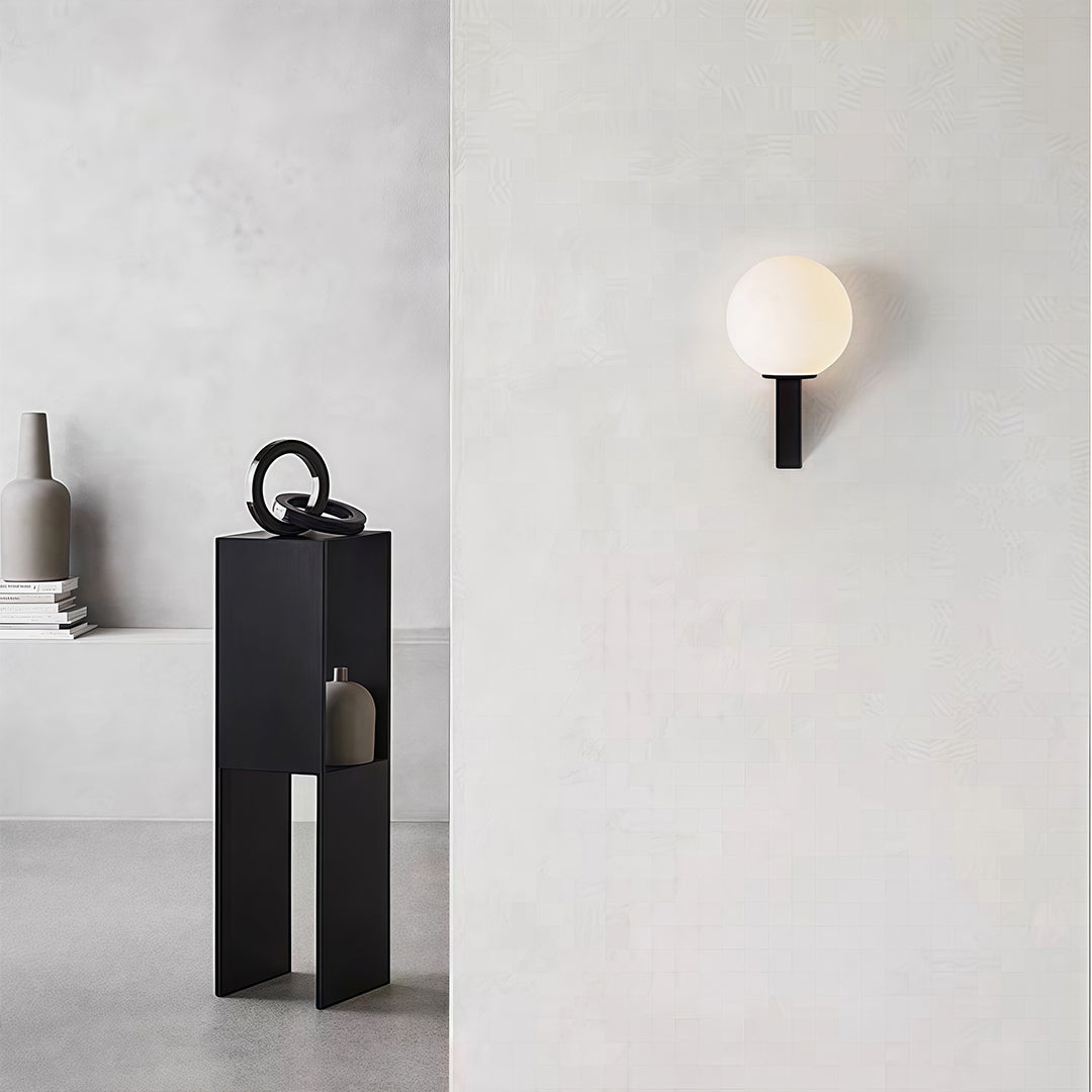 Minimalist frosted globe wall light on a black vertical mount, providing soft, ambient light in a clean, contemporary space.