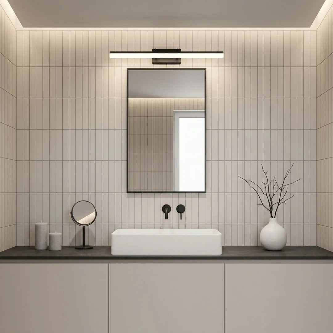 Minimalist gold bathroom vanity light above a narrow mirror in a modern gray bathroom.