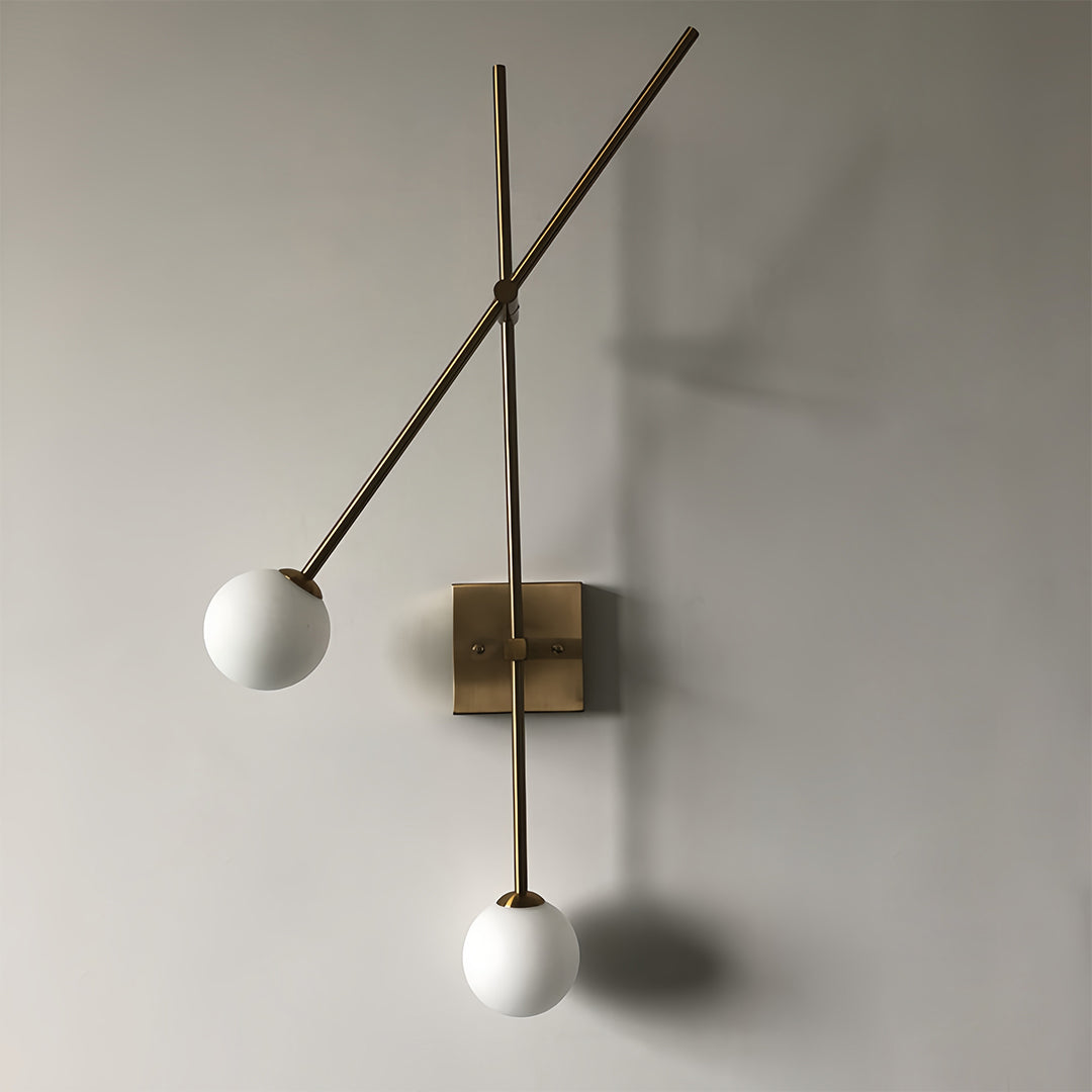 Close-up of a minimalist gold linear wall light with adjustable arms and spherical bulbs