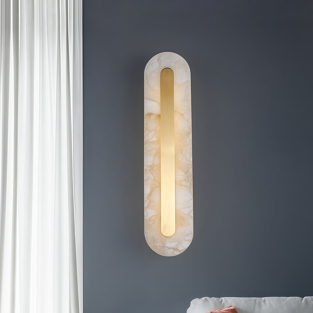 Minimalist gold wall light featuring glass shade chandelier styling creating soft uplighting and downlighting on blue accent wall.