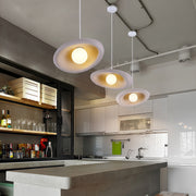 Minimalist Japanese pendant lights featuring glass shade chandelier styling in multiple white discs over kitchen island.