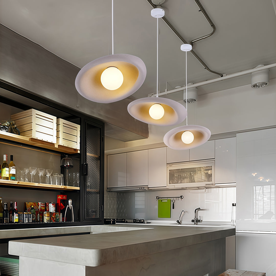 Minimalist Japanese pendant lights featuring glass shade chandelier styling in multiple white discs over kitchen island.